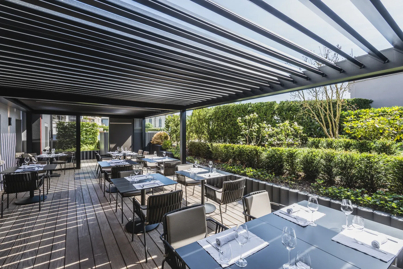 Lamellendach über gedeckten Tischen einer Restaurantterrasse
